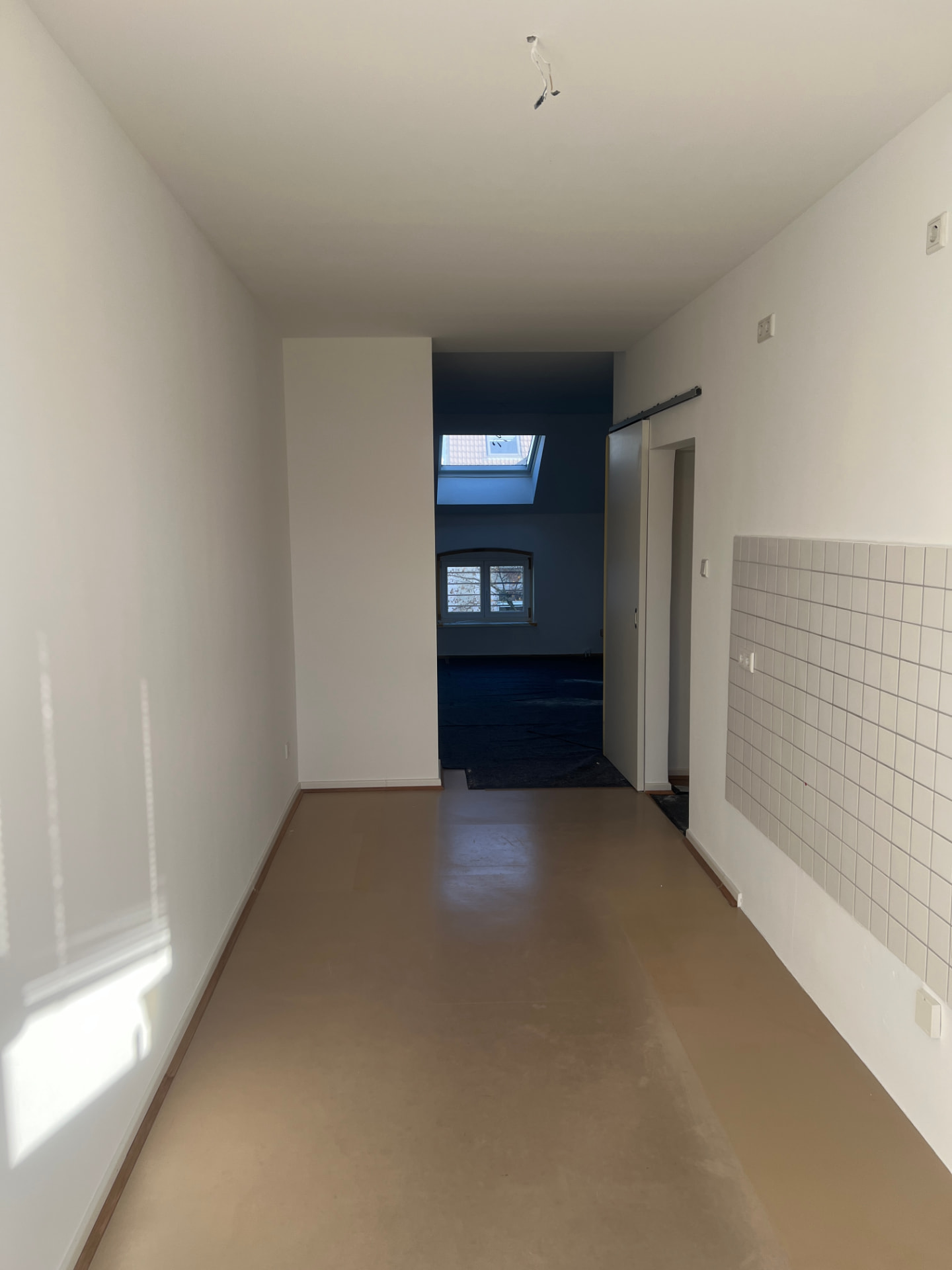 Heller fertig gestrichener Flur mit Dachfenster und Fliesenspiegel
