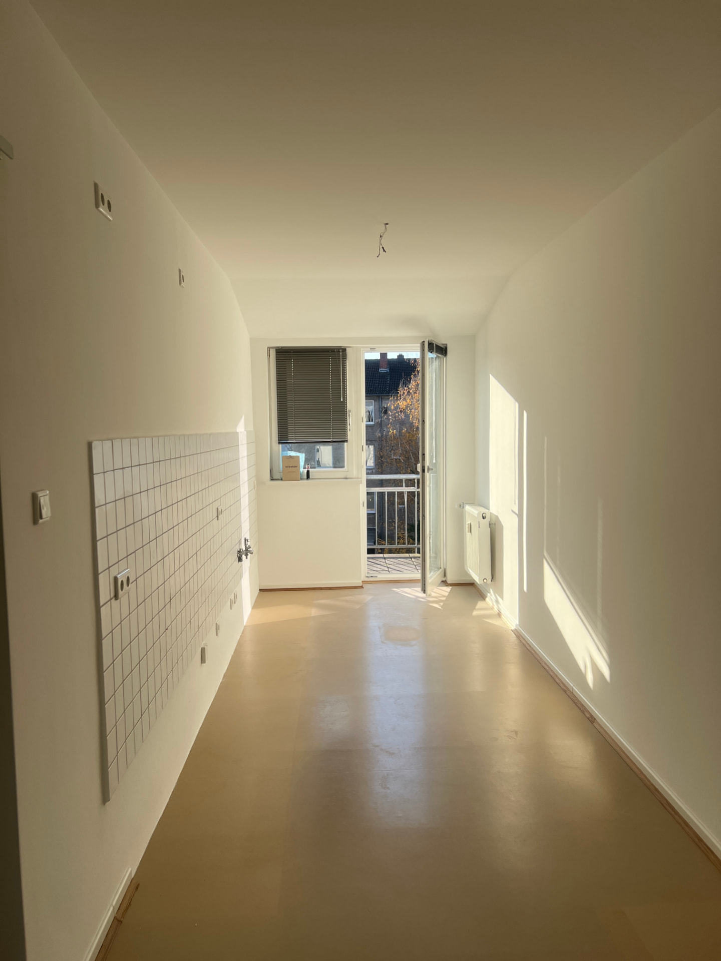 Fertig gestrichener heller Raum mit Balkonzugang und einfallendem Sonnenlicht