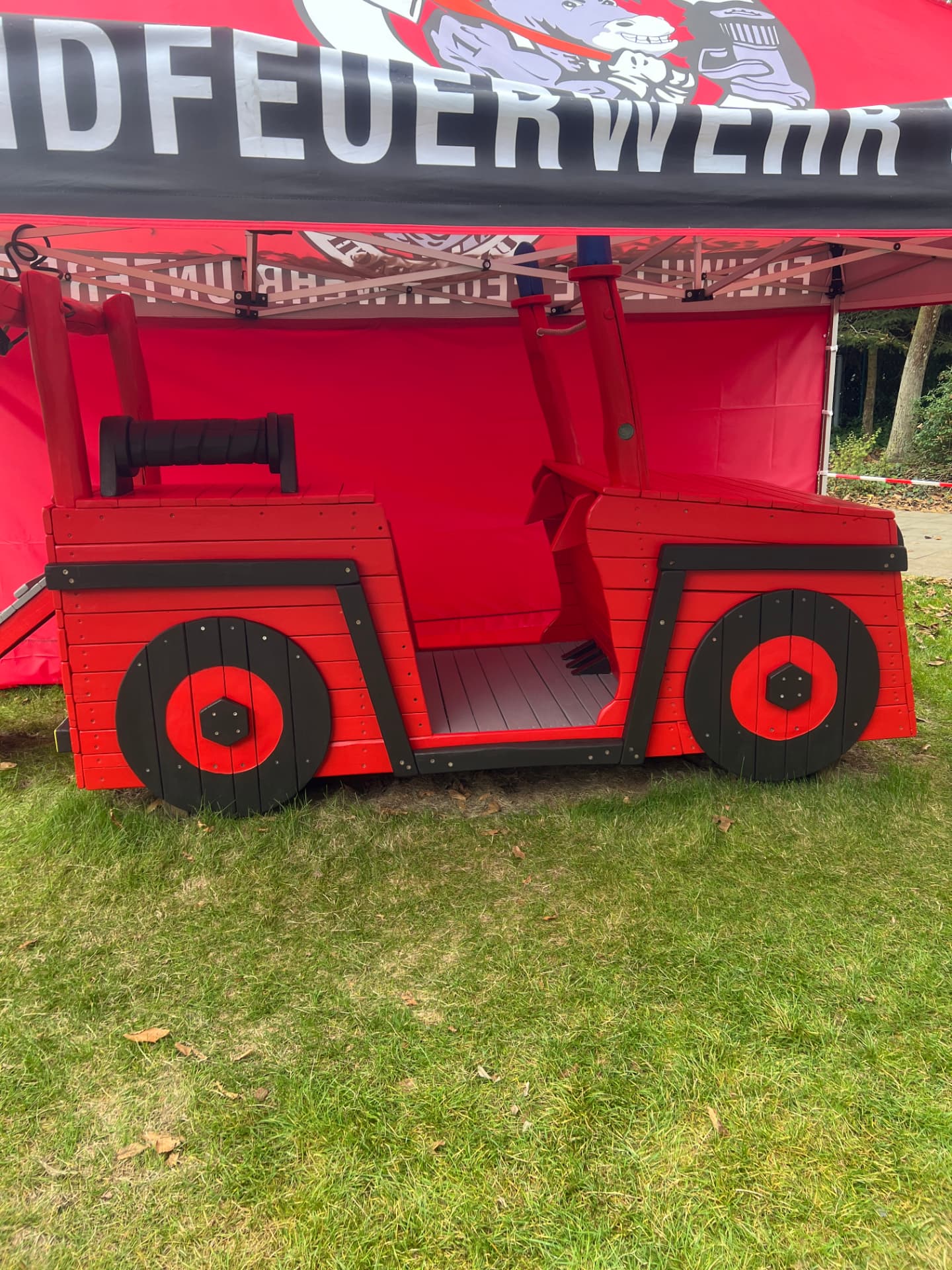 Seitenprofil des Feuerwehr-Spielautos unter einem Pavillon