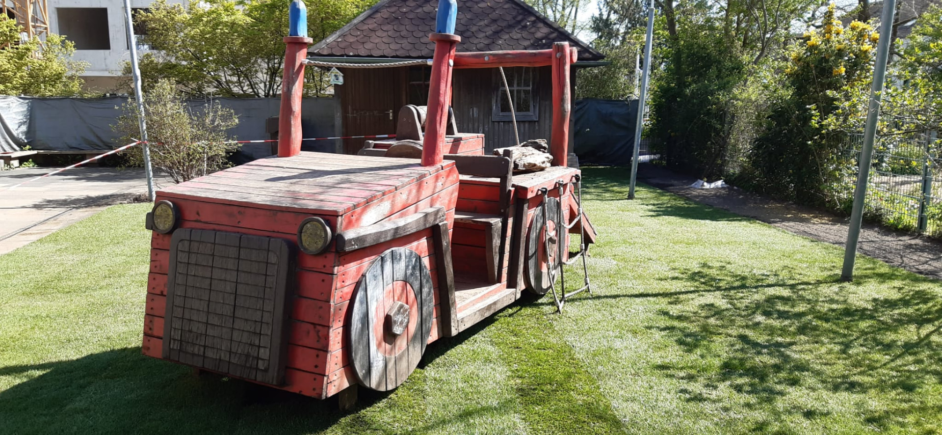 Rotes Feuerwehr-Spielauto auf einer Grünfläche in der Gesamtansicht